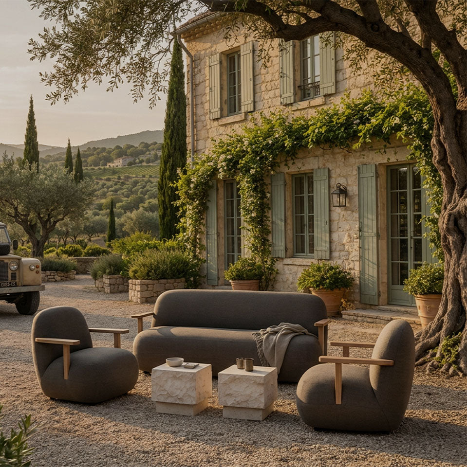 Modern outdoor Toe patio furniture set in a rustic Italian villa courtyard, featuring a dark gray three-seat sofa, two matching Toe armchairs with light wood armrests, and two Limestone Temple tables.