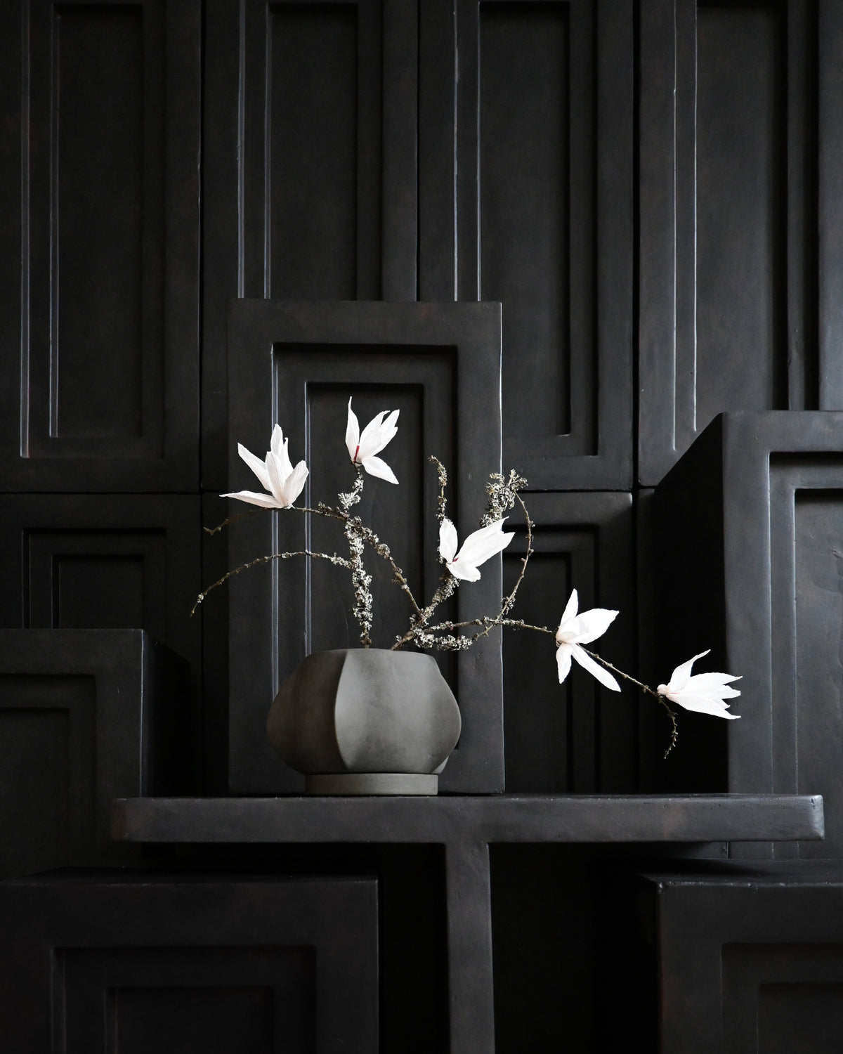 Decorative Arket Plant pot with white flowers in front of a wall of Podiums