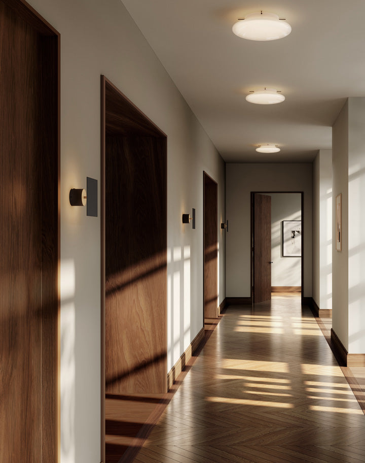 101 Copenhagen Chameleon Wall lamp lit , hanging on the wall of a long hallway