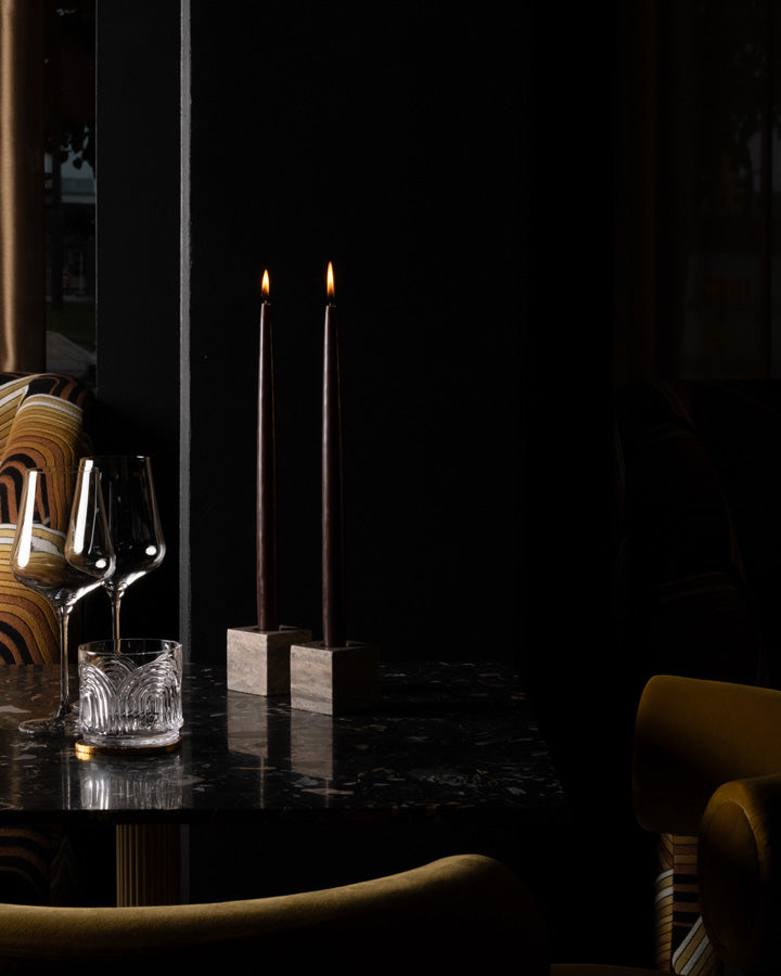 Two lit candles in Cube candle holders on a cozy dining table