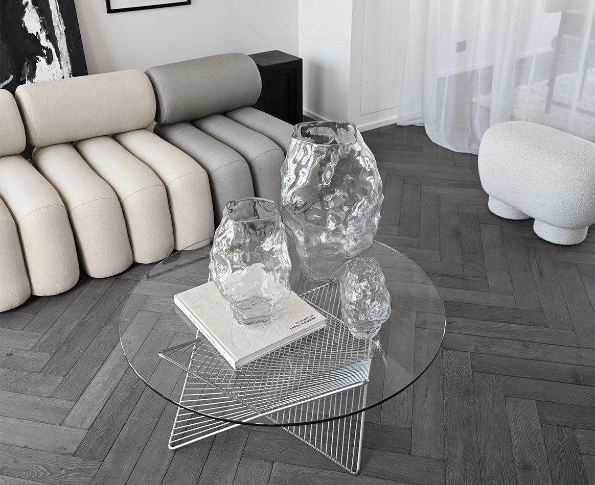 Modern living room with a glass coffee table, decorative Katashi vases, and Foku lounge chairs and Big foot bench in Petit.